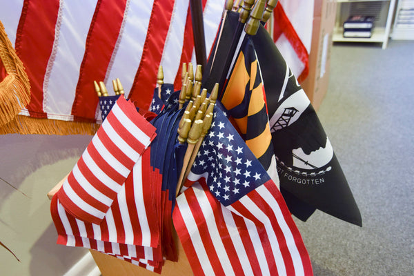 Small American and military stick flags displayed together in-store at Kengla Flag Co.
