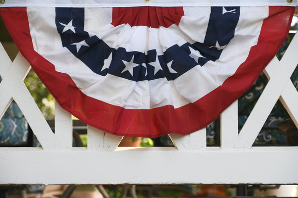 Pleated American flag bunting draped over a white porch railing at Kengla Flag Co.