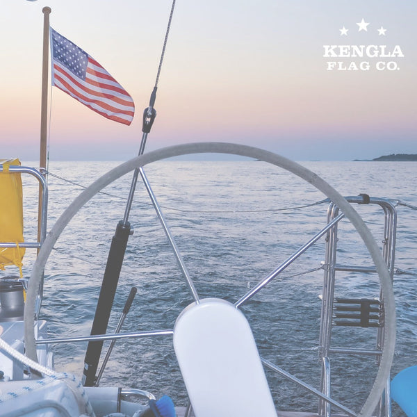 American flag flying from a sailboat at sunset on open water, capturing safe-boating spirit for our nautical signal guide
