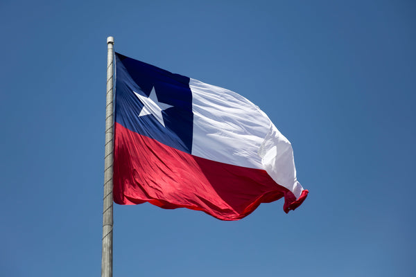 Texas flag waving against a clear sky at Kengla Flag Co.