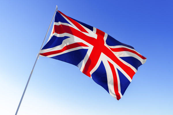 Kengla Flag Co. United Kingdom flag flying from a white pole against a bright blue sky.