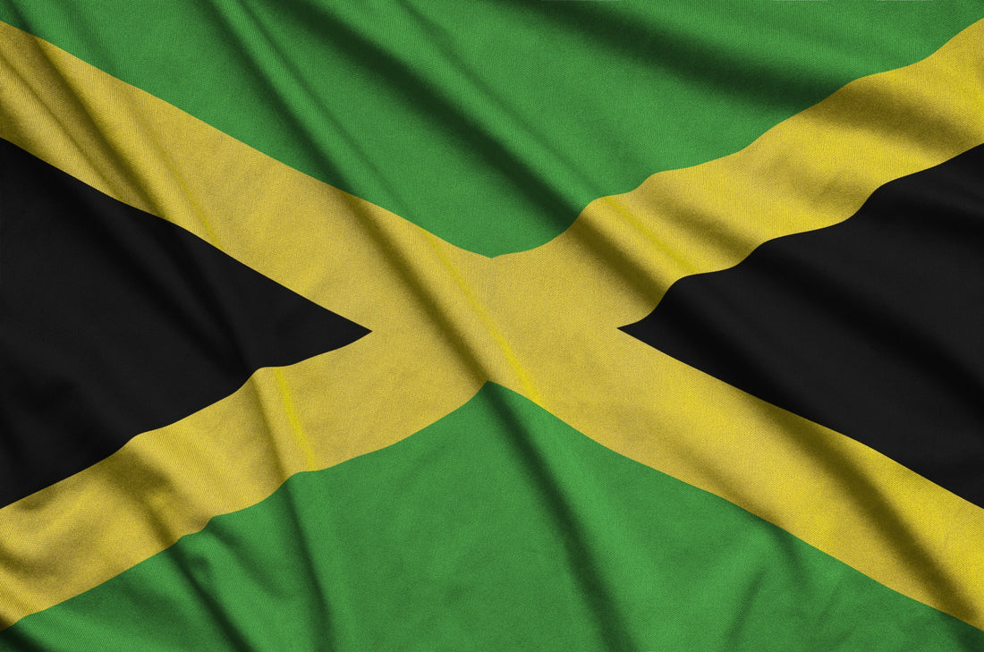 Close-up of the Jamaican flag featuring a gold saltire with green and black triangles on textured fabric.