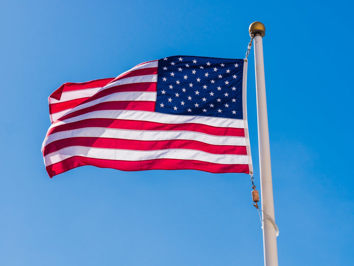 American flag flying on a flagpole against a clear blue sky.